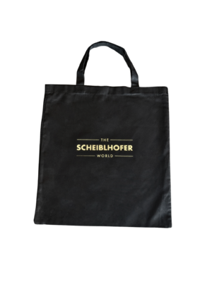 Black carrier bag with The Scheiblhofer World printed in gold letters on the front.