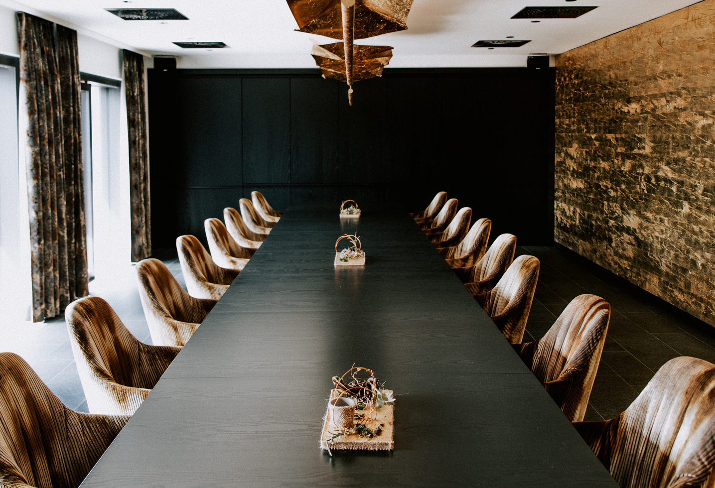 Ein moderner Konferenzraum mit einem langen Tisch, stilvollen Stühlen und dekorativen Tafelaufsätzen.