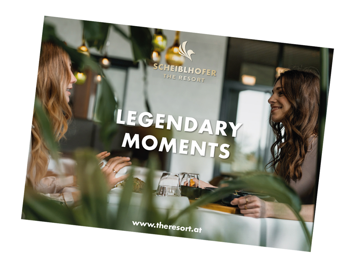 Zwei Frauen lächeln und unterhalten sich an einem Tisch mit Text: Legendäre Momente und eine Resort-Website.