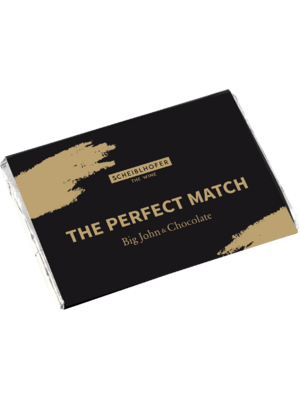 A chocolate bar in black packaging with the inscription The Perfect Match: Big John & Chocolate from Scheiblhofer.