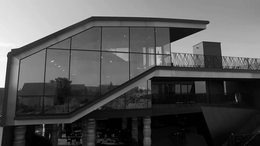 Modernes Gebäude mit großen Glasfenstern und kantiger Architektur, aufgenommen in Schwarz-Weiß.